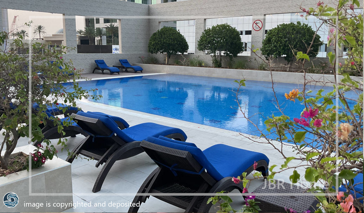 photo of swimming pool in Royal Oceanic Tower in Dubai with green leaves and a person in swimming pool